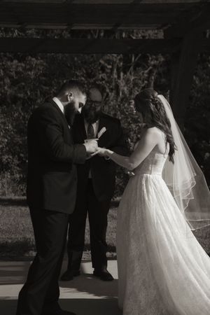 Wedding ceremony moment captured outdoors with bride in flowing white gown.