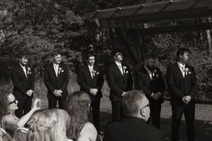 Wedding party stands together outdoors during formal ceremony under natural lighting.