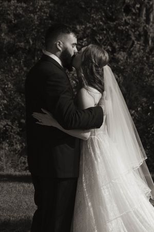 Intimate moment during outdoor wedding ceremony with bride in flowing white gown.