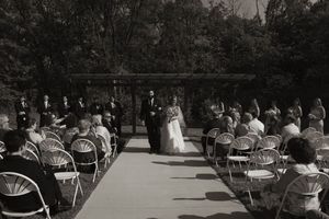 Wide shot of outdoor wedding ceremony with rows of chairs and guests.