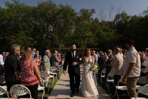 Newlyweds walk down the aisle while wedding guests stand in celebration.