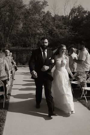 Wedding guests seated in white chairs at outdoor ceremony venue.