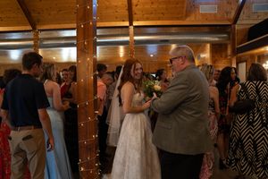 Wedding reception takes place in a rustic wooden venue with string lights.