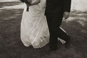 Black and white photo of a bride's flowing dress train during a wedding ceremony.