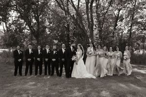 Wedding party lines up for formal photos in an outdoor setting.