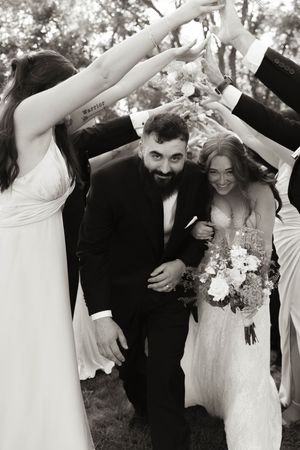 Wedding party forms a tunnel with their arms for a celebratory moment.