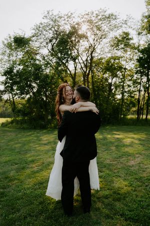 Newlyweds embrace lovingly in a sun-dappled field during their wedding photo session.