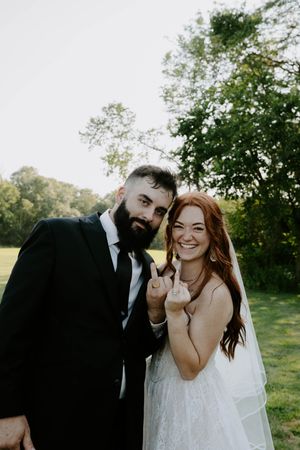 A playful wedding photoshoot captures candid laughter between the couple in a natural setting.