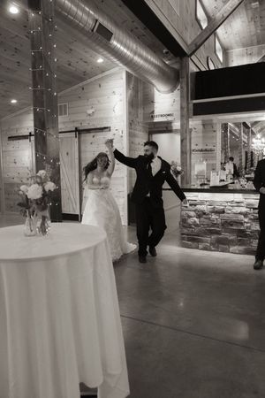 Wedding couple dancing in an industrial-style venue with string lights overhead.