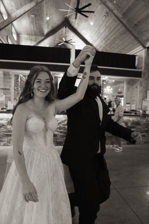 Joyful wedding dance sequence captured in a rustic indoor venue with wooden beams.
