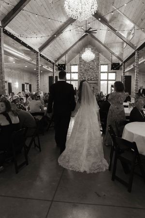 Wedding guests dancing and celebrating in a barn-style venue decorated with twinkling lights.