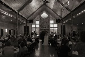Wedding reception venue with rustic wooden beams, chandeliers and string lights creating a romantic atmosphere.