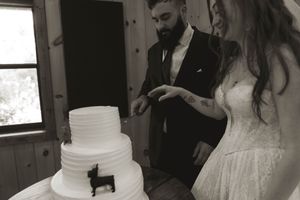Elegant white tiered wedding cake displayed at a rustic wooden venue.