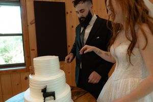 Wedding cake cutting moment in a rustic wooden paneled room.