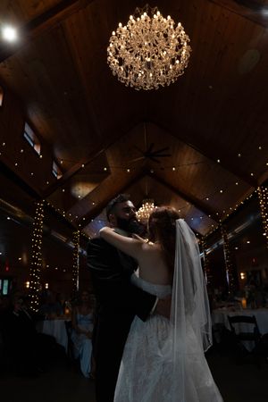 Romantic first dance moment under an ornate crystal chandelier at wedding reception.