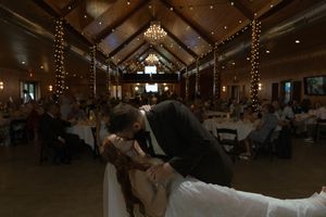 Dancers twirl beneath twinkling lights and wooden beams during an evening wedding reception.