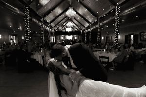 A romantic dance sequence at a wedding reception with string lights and a chandelier overhead.