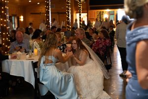 Wedding guests dancing and celebrating under decorative string lights in a rustic venue.