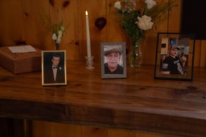 Memorial photos and flowers displayed on a wooden table at a wedding reception.