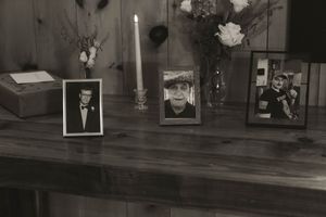 A collection of framed photographs and floral arrangements on a dark wooden surface.