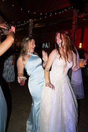 Celebration on the dance floor with guests in flowing dresses under ambient string lights.