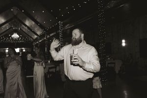 Wedding guests dancing and celebrating at a reception under twinkling lights in a rustic venue.