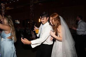 Wedding party dancing enthusiastically on the dance floor under string lights.