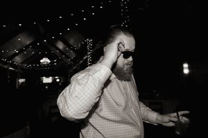 Black and white photo of someone dancing expressively at a wedding reception.