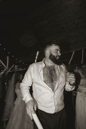 Guest enjoying the wedding celebration with an unbuttoned shirt on the dance floor.