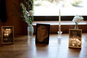 Wedding memorial tribute with vintage photos, white flowers and candles in glass bottles.