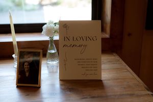 Memorial table setting with 'In Loving Memory' card, frames and delicate white flowers.