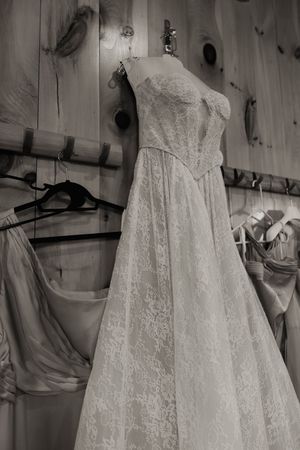 Elegant white lace wedding dress hanging on display with intricate embroidered details.