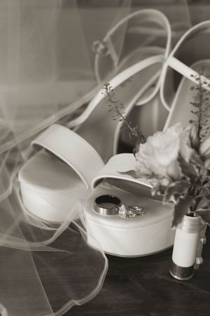 Wedding accessories including white ribbon and decorative items arranged on a dark surface.
