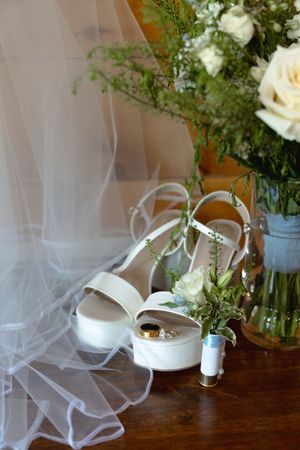 White roses and delicate tulle arranged with greenery on a wooden table surface.