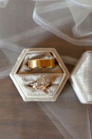 Close-up of wedding rings displayed in an elegant hexagonal white box with delicate details.