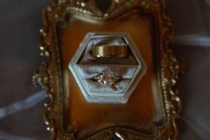 Wedding rings nestled in an ornate gold vintage frame with decorative details.