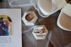 Wedding details including invitation and decorative elements arranged on a wooden surface.