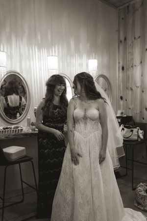Black and white photo of wedding dress preparation in rustic wooden room.