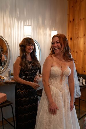 Joyful moment captured in bridal suite with wedding dress and black lace dress.