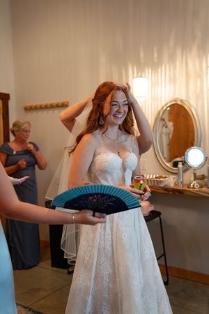 Final wedding dress adjustments in rustic bridal suite with natural lighting.