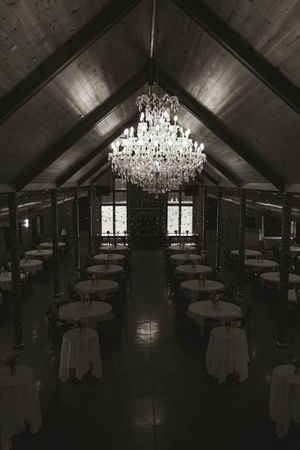 Elegant reception hall with crystal chandelier and round tables set for wedding celebration.