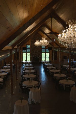 Wedding reception space with vaulted wooden ceiling and elegant crystal lighting fixtures.