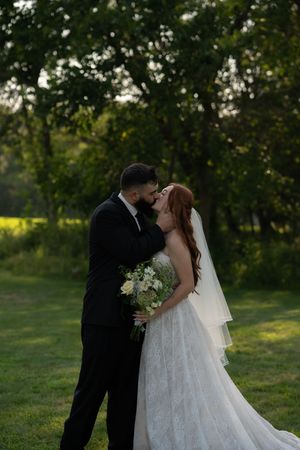 Newlyweds share an intimate moment in a lush green garden setting.
