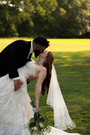 Romantic wedding sequence showing a dip pose between a bride and companion on grassy lawn.