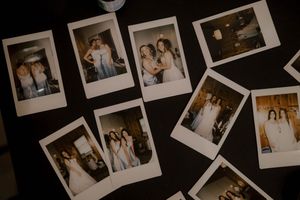 Multiple polaroid photographs scattered on dark surface showing wedding celebration memories.