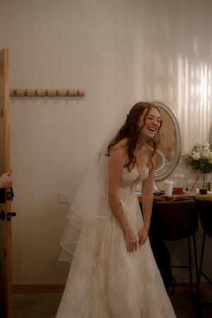 A joyful moment captured in a getting ready room with white lace wedding dress and veil.