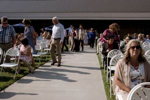 Wedding guests gather outdoors under a covered walkway during a summer celebration.