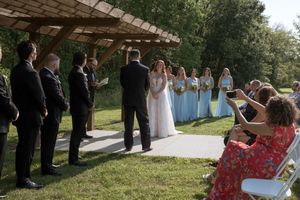 Wedding guests gather along a covered walkway during an outdoor celebration.