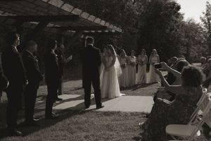 Wedding guests line up along a covered walkway during an outdoor ceremony.