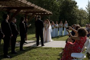 Guests watch the wedding procession from a covered outdoor walkway.